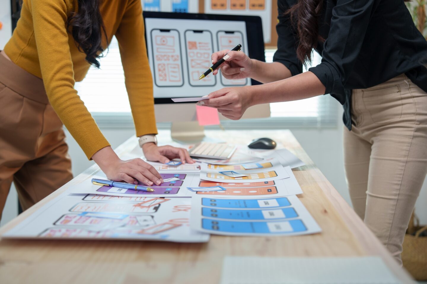 Two female ux ui designers are discussing mobile app templates, working together to enhance user exp