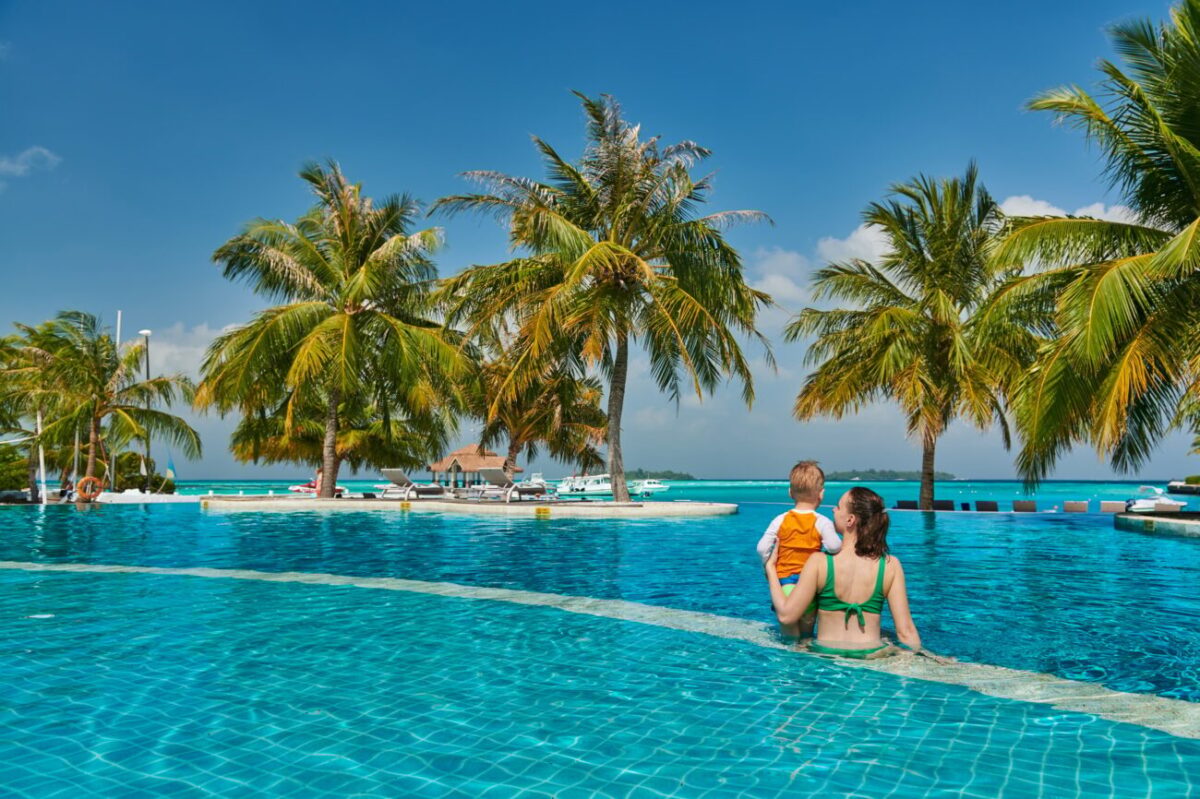 Toddler boy in resort swimming pool with mother