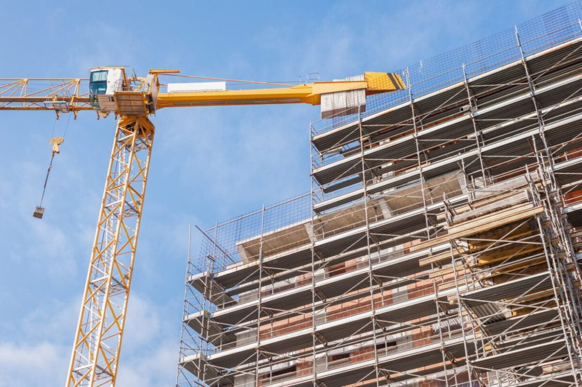 Building under construction with building armor and a crane.